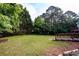 A view of the large backyard with luscious grass, wood deck, trees and flower bed at 620 Reeves Hill Pt, Lawrenceville, GA 30043