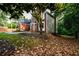 Beautiful view of house and side yard with leaves on ground and a green treed backdrop at 620 Reeves Hill Pt, Lawrenceville, GA 30043