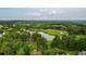 Scenic aerial view showcasing a lush golf course, a tranquil pond, and beautiful surrounding trees at 7025 Kettering Ln, Suwanee, GA 30024