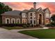 Elegant stone and stucco home with manicured lawn, mature landscaping, and a welcoming entrance at sunset at 7025 Kettering Ln, Suwanee, GA 30024