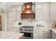Close up of kitchen with stainless steel appliances, granite counters, and wood hood at 7025 Kettering Ln, Suwanee, GA 30024