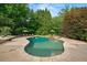 Backyard pool surrounded by stone with wooded border and lounge seating area at 7025 Kettering Ln, Suwanee, GA 30024