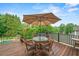 An outdoor dining area on a wooden deck with seating for four, offering a scenic view of the lush greenery at 7025 Kettering Ln, Suwanee, GA 30024