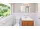 Bright bathroom featuring white tiled walls, a wooden vanity, and a view to the greenery outside at 3170 Bellgreen Way, Decatur, GA 30032