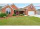 Charming brick home featuring a manicured lawn, inviting front porch, and an attached two-car garage at 1382 Fountain Lakes Drive Dr, Lawrenceville, GA 30043