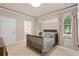 Cozy bedroom with neutral tones, a wood-frame crib, and natural light from the large windows at 10630 N Edgewater Pl, Johns Creek, GA 30097