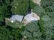 A high aerial view of the home shows its location among the trees, driveway, and deck with outdoor dining set at 543 S Holly Springs Rd, Woodstock, GA 30188