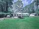 Expansive backyard with lush green grass, mature trees, a deck, an outdoor dining area and a playhouse at 543 S Holly Springs Rd, Woodstock, GA 30188