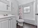 Bright bathroom featuring a white vanity, toilet, and shower-tub combo with colorful curtain at 543 S Holly Springs Rd, Woodstock, GA 30188