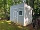 Outdoor utility shed with white trim and doors, positioned in a private backyard at 185 Colemans Bluff Dr, Woodstock, GA 30188