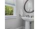 Powder room featuring a pedestal sink, modern faucet, and a round decorative mirror at 1865 Henley Way, Alpharetta, GA 30009