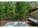 Wood deck with wooden railing featuring an outdoor bench that overlooks mature green trees at 7875 Robin Rd, Cumming, GA 30041