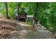 Exterior of home featuring elevated deck, wooded lot, landscaping, and ramp at 7875 Robin Rd, Cumming, GA 30041