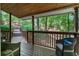 Inviting covered porch with wooden railings, cozy seating and views of the lush greenery at 7875 Robin Rd, Cumming, GA 30041