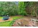 View of the fenced-in backyard with mature trees, trampoline, and fire pit at 4274 Timber Trace Road, Loganville, GA 30052
