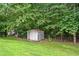 View of a backyard with a storage shed surrounded by lush trees and a chainlink fence at 4274 Timber Trace Road, Loganville, GA 30052