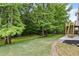Well-maintained backyard featuring a brick pathway, lush greenery, and a wooden deck with stairs at 1897 Alcovy Trace Way Way, Lawrenceville, GA 30045