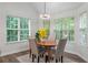 Inviting dining area with wood table, neutral chairs, modern chandelier, and natural light from multiple windows at 2701 Windsor Nw Ct, Kennesaw, GA 30144