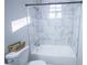 Bathroom featuring a bathtub and shower combo with marble-look tiled walls and a small window for natural light at 3893 Bonnie Se Ln, Atlanta, GA 30354
