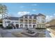 Rear of luxury home featuring a covered balcony and manicured landscaping with a small fountain at 100 Pine Mist Cir, Alpharetta, GA 30022