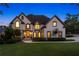 Charming two-story home with beautiful front lawn and warm, inviting exterior lighting at dusk at 100 Pine Mist Cir, Alpharetta, GA 30022