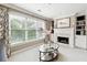 Cozy living room with a fireplace, built-in bookshelves, and large windows overlooking the landscaped yard at 100 Pine Mist Cir, Alpharetta, GA 30022