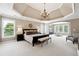 Spacious main bedroom with a tray ceiling, large windows, and an elegant chandelier at 100 Pine Mist Cir, Alpharetta, GA 30022