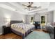 Spacious bedroom featuring a ceiling fan, natural light, wood floors, and a comfortable seating area at 1019 Legacy Walk, Woodstock, GA 30189