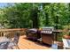 Deck featuring wood floors, grilling area, a table and chairs, and a view of the surrounding woods at 1019 Legacy Walk, Woodstock, GA 30189