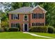 Charming two-story brick home with manicured lawn and mature trees, complete with black shutters and a classic front door at 1019 Legacy Walk, Woodstock, GA 30189