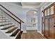 Bright foyer with hardwood floors, elegant staircase, arched doorway and stylish light fixture offers a warm welcome at 525 Wallis Farm Ln, Marietta, GA 30064
