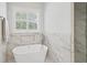 Main bathroom featuring marble walls, tile floors, soaking tub, and separate glass shower at 1323 Frey Lake Ct, Kennesaw, GA 30144
