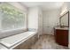Bright bathroom with a soaking tub by a large window and a granite vanity with double doors for storage at 410 Glenmont Ct, Atlanta, GA 30350