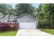 Attached two-car garage with a concrete driveway and gray siding surrounded by beautiful landscaping at 2983 Crosswycke Forest Dr, Brookhaven, GA 30319