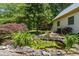 Zen backyard waterfall feature with lush plants, natural stone, and a lily pad filled pond at 3175 Lake Seminole Pl, Buford, GA 30519