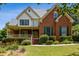 Charming two-story brick home with a welcoming front porch and lush, landscaped front yard at 3175 Lake Seminole Pl, Buford, GA 30519