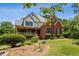 Two-story home with brick exterior, covered front porch, and mature trees on a sunny day at 3175 Lake Seminole Pl, Buford, GA 30519
