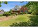 Two-story home with brick exterior, covered front porch, manicured lawn and mature trees at 3175 Lake Seminole Pl, Buford, GA 30519