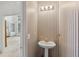 Charming powder room with a pedestal sink, decorative wallpaper, and adjacent doorway view at 3175 Lake Seminole Pl, Buford, GA 30519