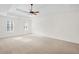 Large empty main bedroom featuring carpeted floors, tray ceiling, fan and shuttered windows at 1801 Summerview Ct, Woodstock, GA 30189