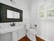 Clean half bathroom with pedestal sink, modern toilet, decorative mirror, and wood floors at 1801 Summerview Ct, Woodstock, GA 30189