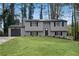 Charming two-story home with gray siding, a well-manicured lawn, and a paved driveway leading to an attached garage at 3414 Dearwood Sw Dr, Lilburn, GA 30047