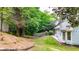 Serene backyard featuring a grassy area, mature trees, and a home exterior in a tranquil setting at 507 Huntgate Rd, Woodstock, GA 30189