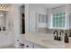 Bright bathroom featuring double sinks with marble countertops, a large mirror, and access to a walk-in closet at 3980 Suwanee Place Dr, Suwanee, GA 30024