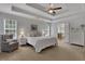 Bedroom with tray ceiling, a chair, two dressers, carpet, and neutral colors at 3980 Suwanee Place Dr, Suwanee, GA 30024