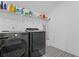 Modern laundry room boasts sleek, black washer and dryer with stylish patterned tile floor and shelving at 4960 Norman Ct, Cumming, GA 30040