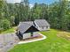 New exterior features white painted brick, vertical siding, black trim, new roof, landscaping, and wooded backdrop at 2725 Glendale Ne Dr, Conyers, GA 30013