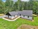 New exterior features white painted brick, vertical siding, black trim, new roof, landscaping, and wooded backdrop at 2725 Glendale Ne Dr, Conyers, GA 30013