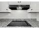 Updated kitchen featuring granite countertops, white cabinets, and a modern electric cooktop at 2725 Glendale Ne Dr, Conyers, GA 30013