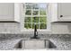 Close-up of a stainless steel kitchen sink with granite counters and a view of mature trees at 2725 Glendale Ne Dr, Conyers, GA 30013
